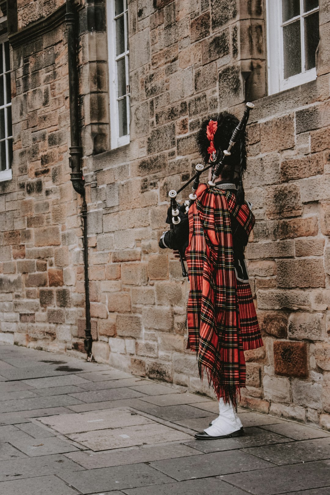 person playing bag pipe on sidewalk