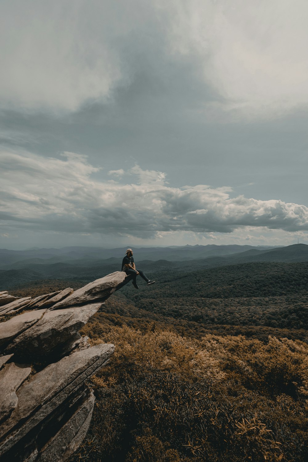 person sitting on brown cliff