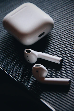 A pair of modern wireless earbuds resting on a soft fabric surface.