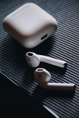 A sleek pair of earbuds resting beside a phone with a matching case.