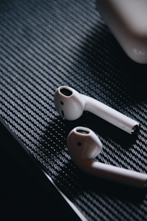 Close-up of sleek wireless earbuds resting on a black surface with subtle blue lighting