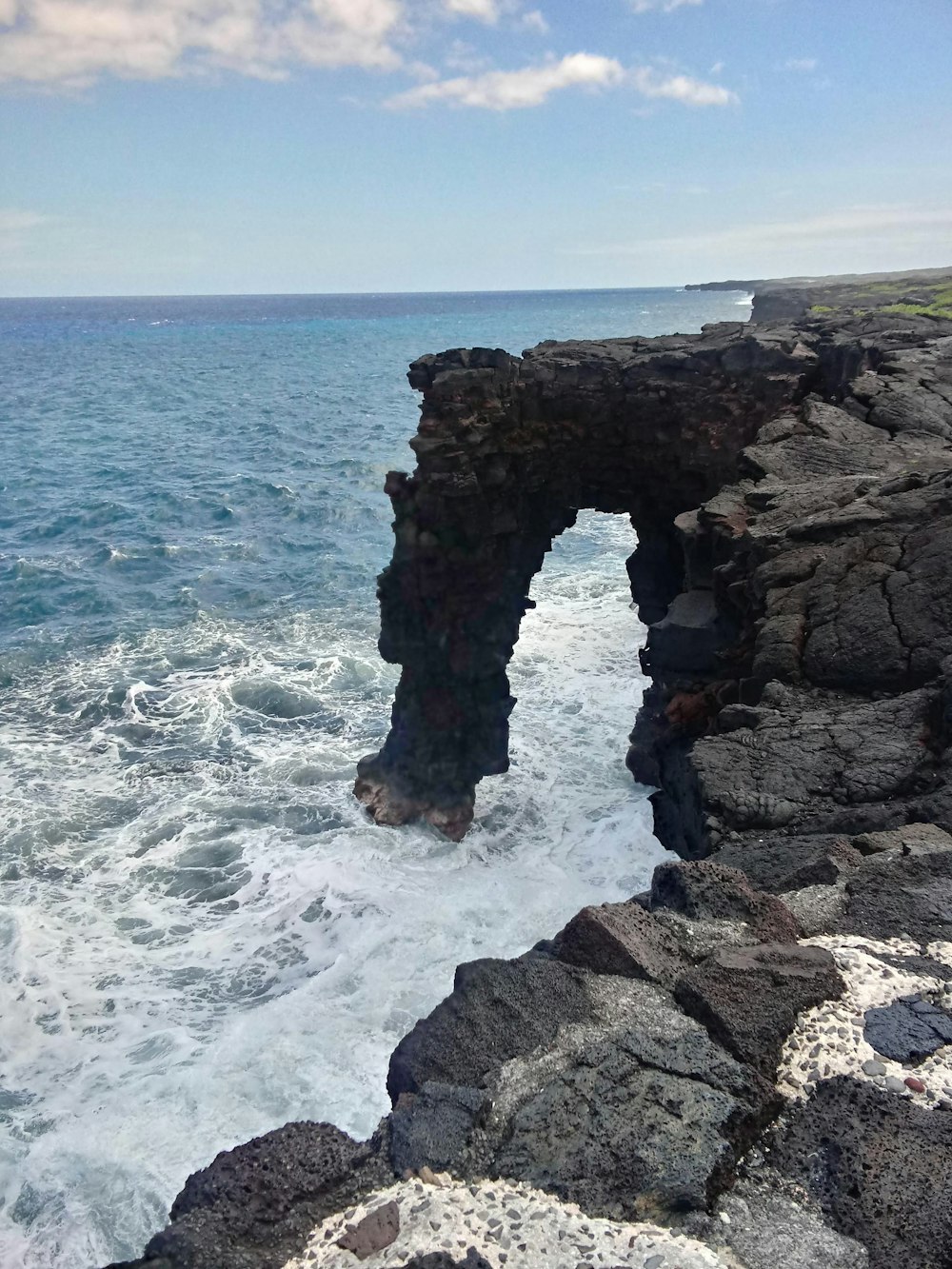 a rocky cliff with a hole in the middle of it