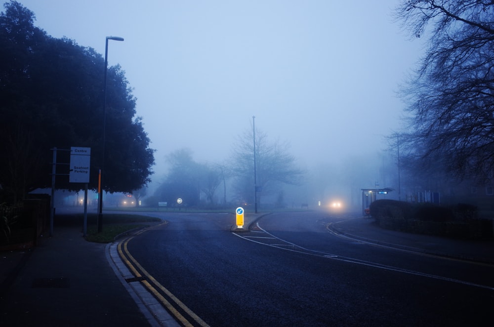a foggy street with a street light on the corner