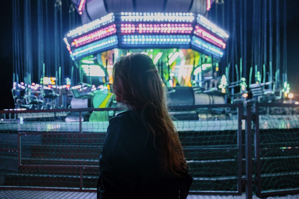 a woman standing in front of a carnival ride at night