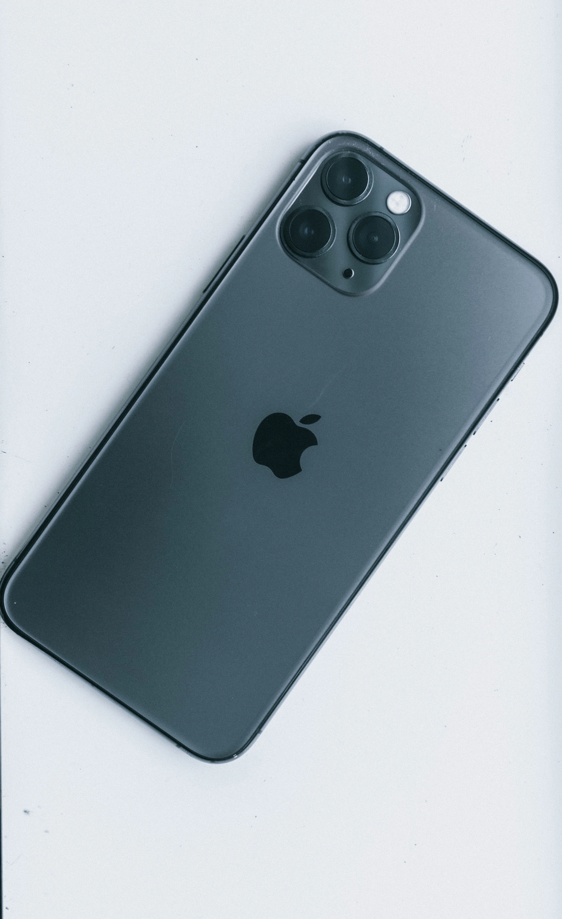A sleek iPhone displaying the cama app's timestamp camera interface with a photo showing GPS coordinates and time overlay on a dark graphite background.