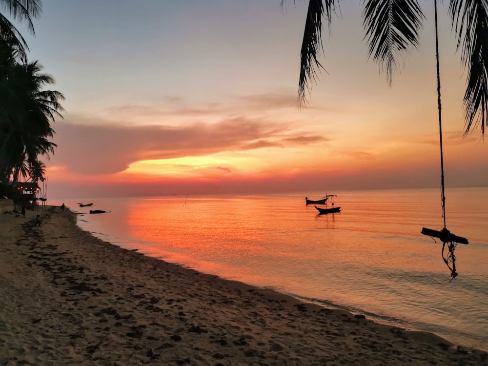 a sunset on a tropical beach with a boat in the water