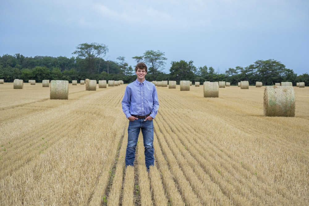 a man standing in a field of hay bales