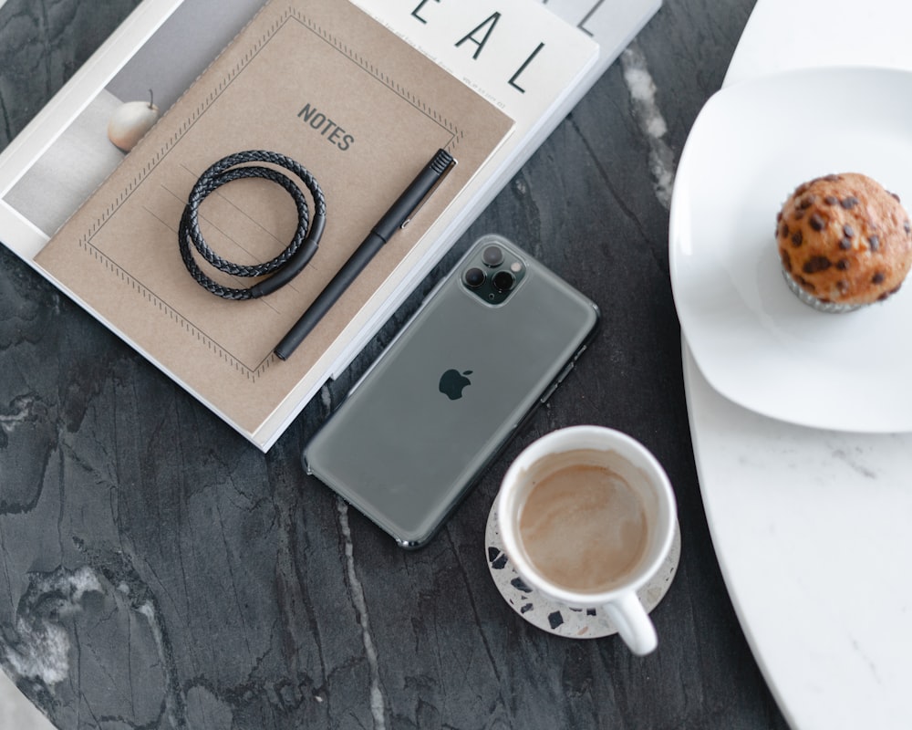 a cup of coffee and a cell phone on a table