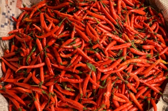 a pile of red peppers sitting on top of a newspaper