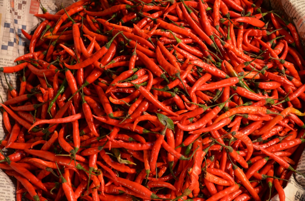 a pile of red peppers sitting on top of a newspaper