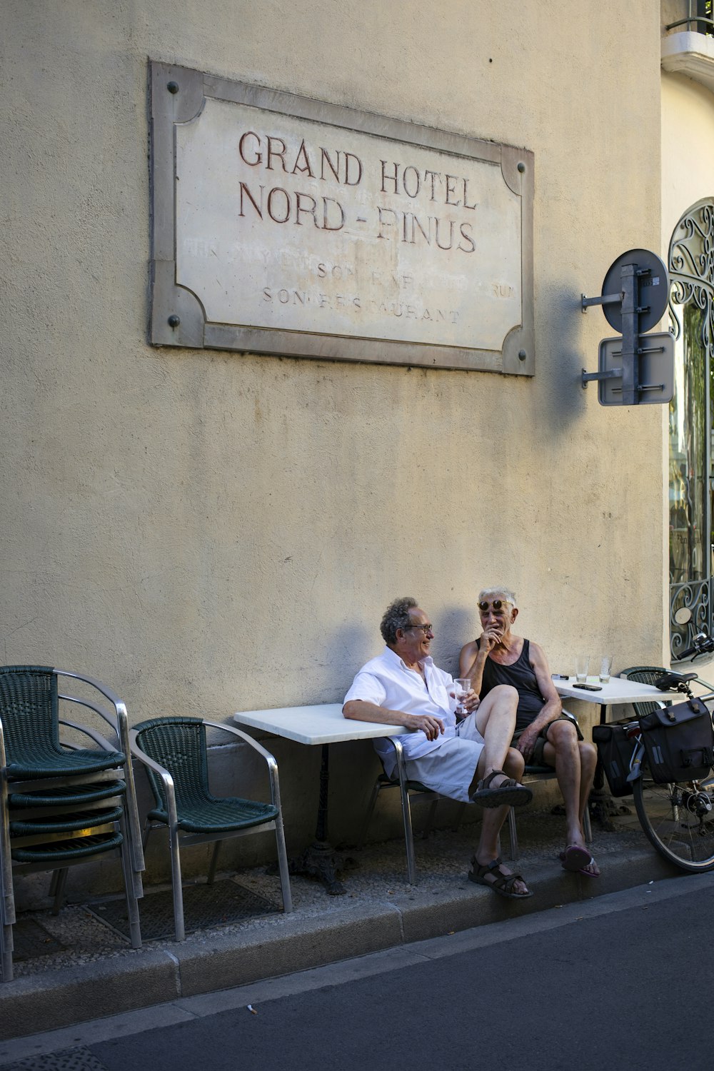 um homem e uma mulher sentados em um banco em frente a um hotel