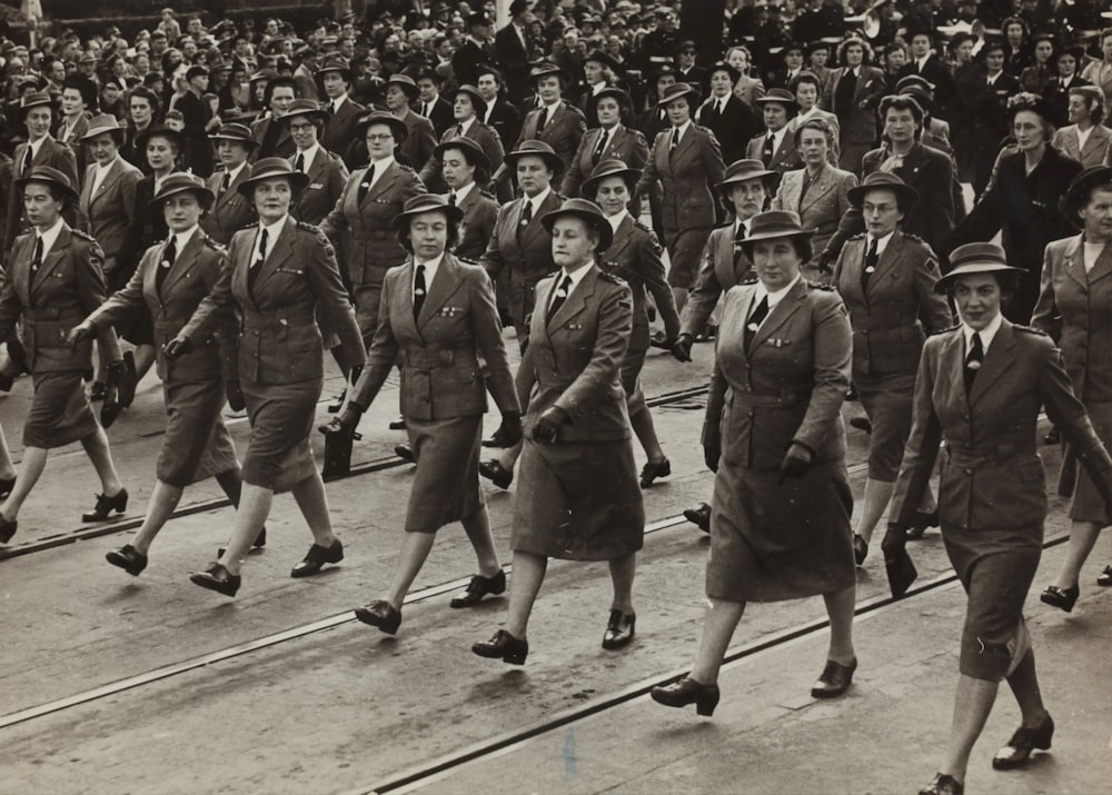 fotografia in scala di grigi di un gruppo di donne che marciano sulla strada