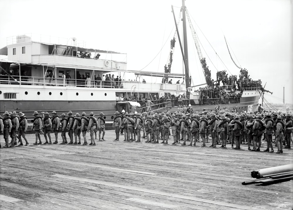 grayscale photography of soldier marching beside passenger ship