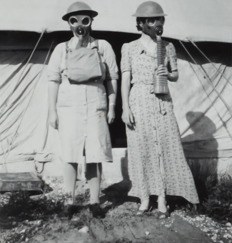 two women wearing gas mask standing beside tent