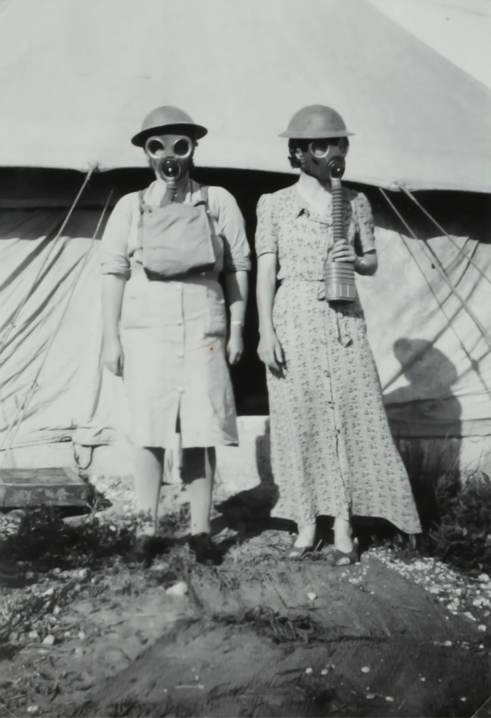 two women wearing gas mask standing beside tent