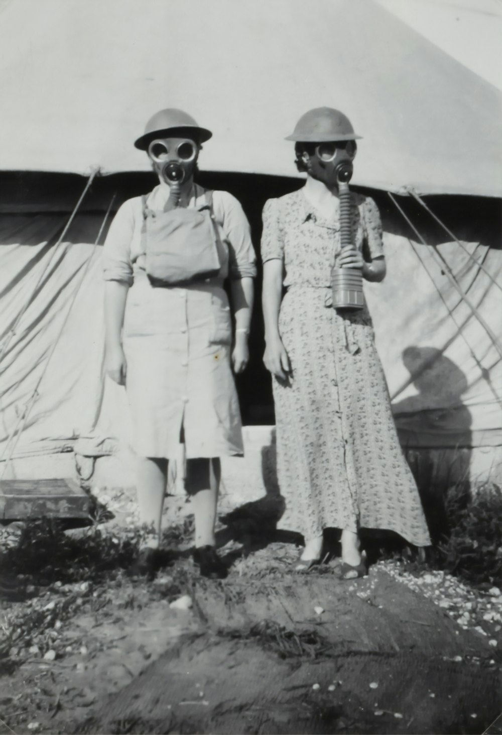 Due donne che indossano una maschera antigas in piedi accanto alla tenda