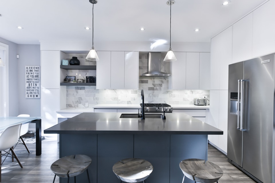 Contemporary kitchen featuring a grey quartz island and a white herringbone tile backsplash—Professional stone fabrication and artisan tile work by LuXe Design Tile and Granite inc..