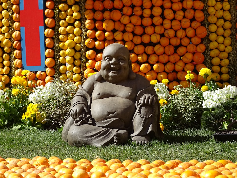 a buddha statue sitting in front of a display of oranges