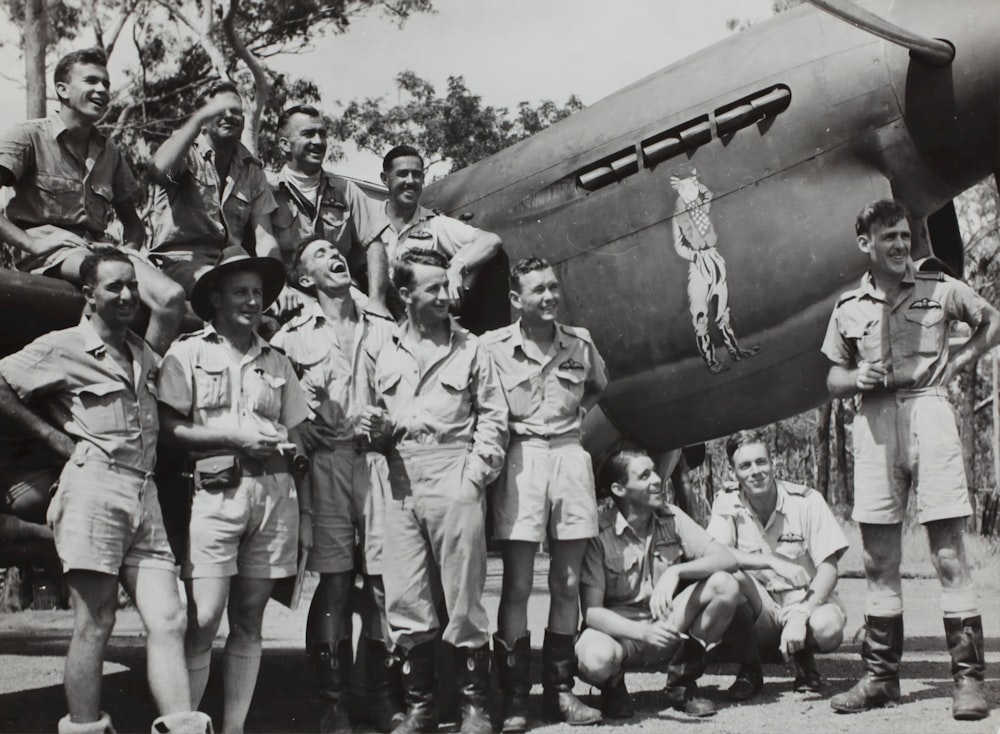 Fotografía en escala de grises de un grupo de hombres junto a un avión de combate