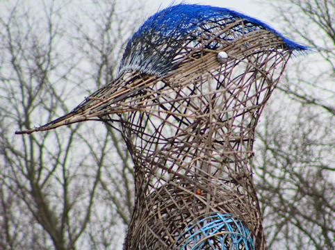 Side view of a string art sculpture depicting a bird in flight with vibrant threads.