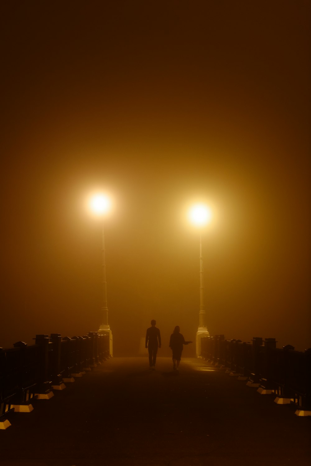 a couple of people walking down a street at night