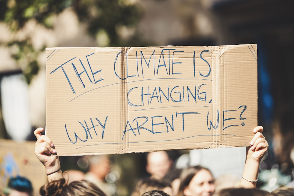 Un groupe de personnes tenant une pancarte qui dit que le climat est en train de changer pourquoi Aren '