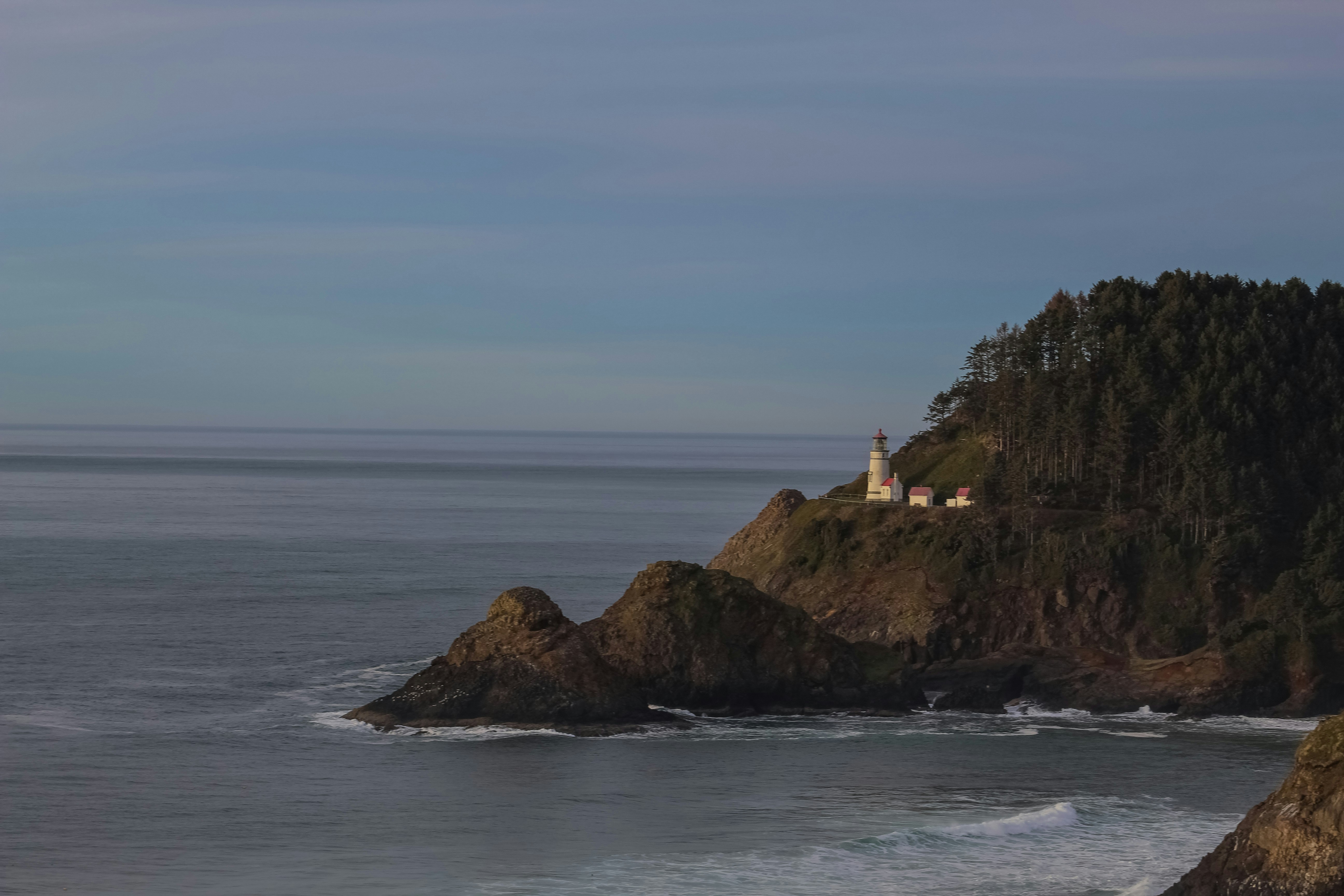 a lighthouse on top of a rocky outcropping next to the ocean