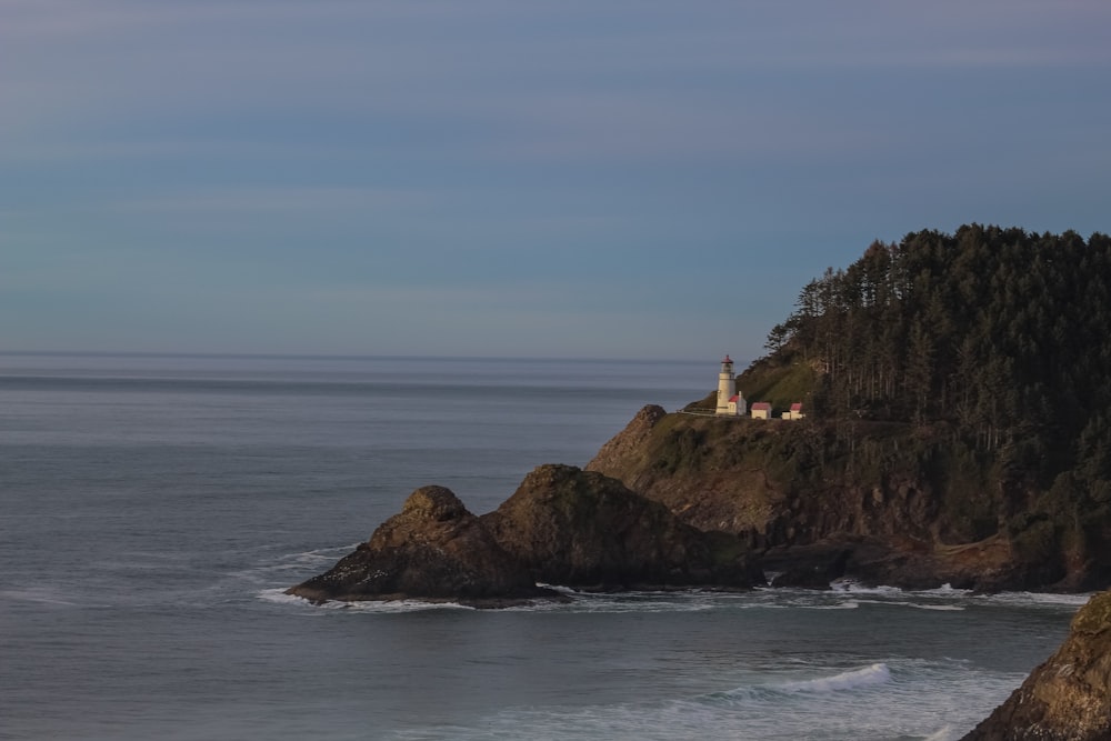 a lighthouse on top of a rocky outcropping next to the ocean