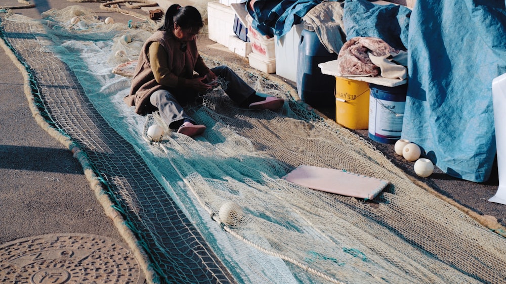 a woman sitting on the ground next to a net