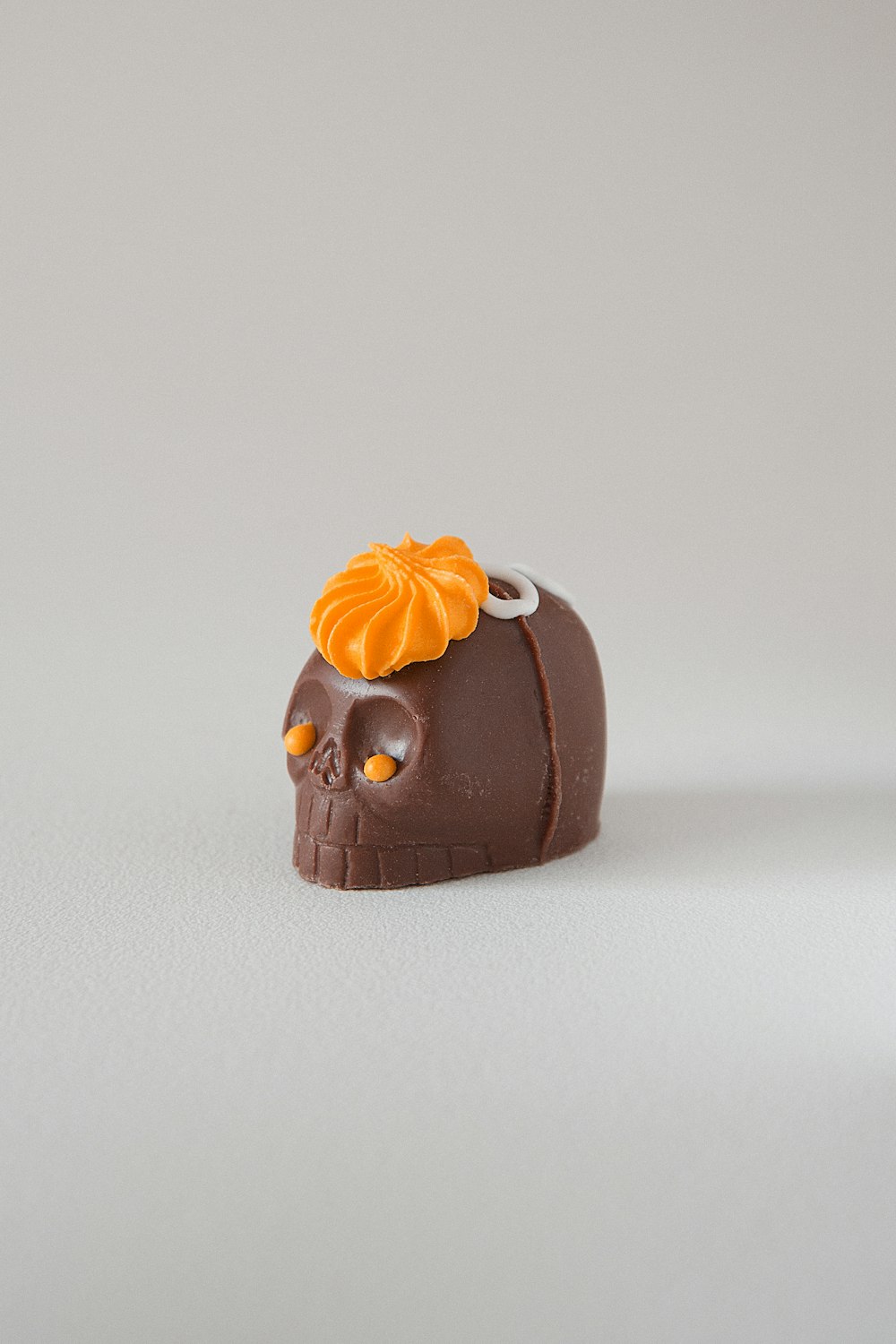 a chocolate skull with an orange flower on its head