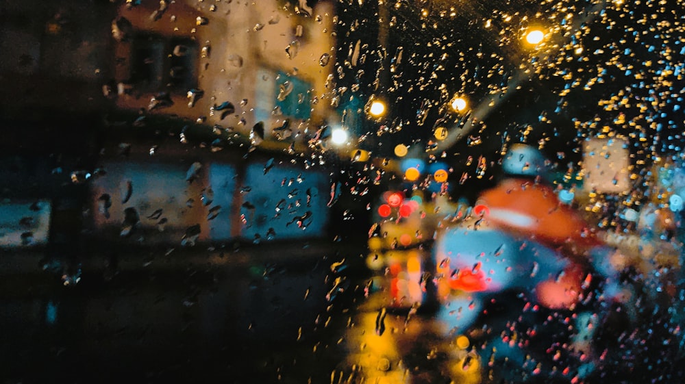 rain drops on a window as cars drive down the street