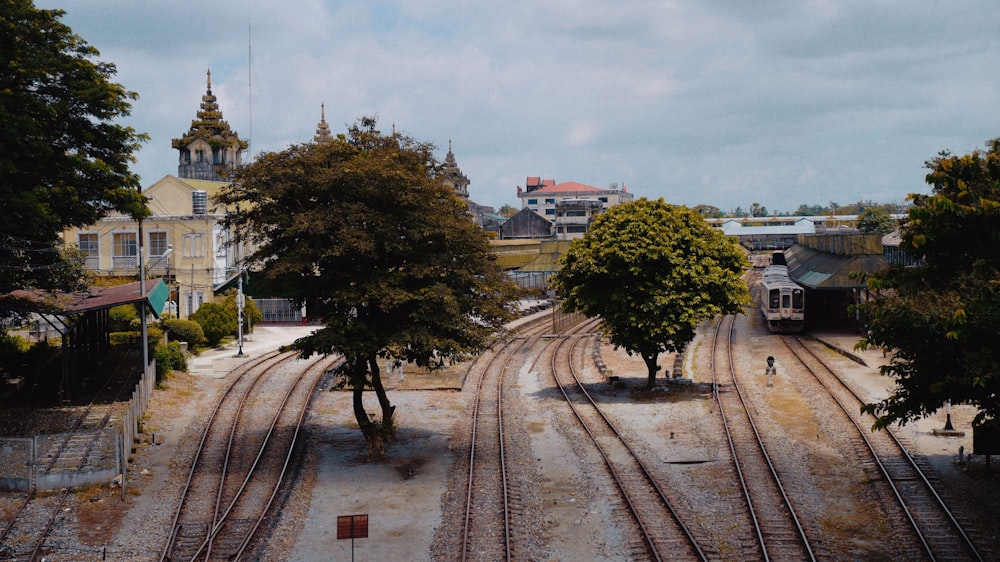 a train track with trees and buildings in the background