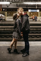 man and woman kissing beside train rails