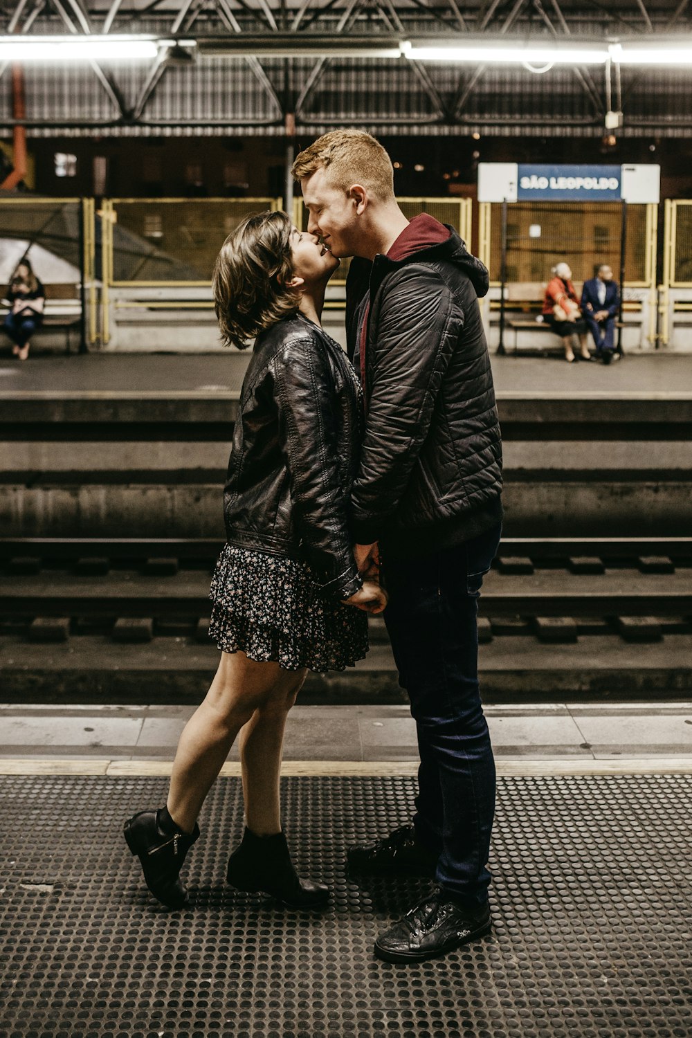 man and woman kissing beside train rails
