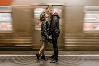 a man and a woman standing in front of a train