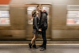 a man and a woman standing in front of a train