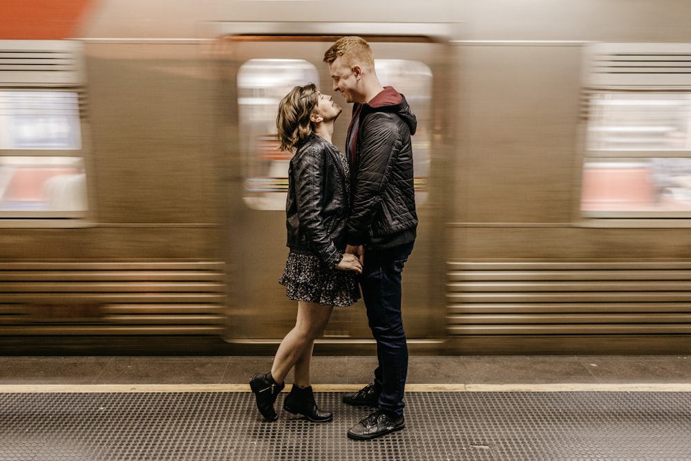 a man and a woman standing in front of a train
