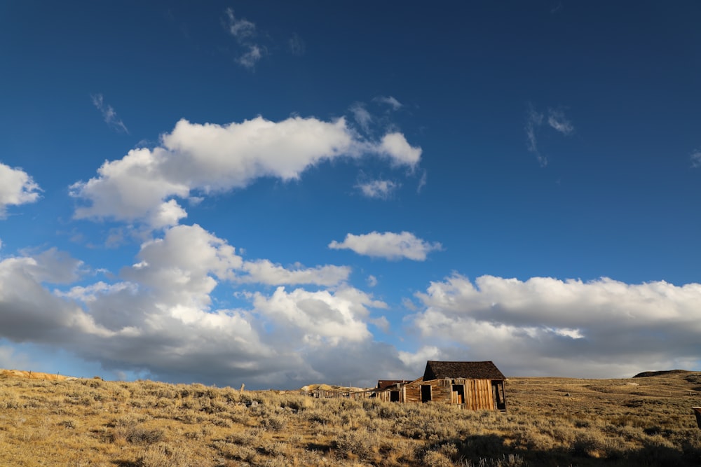 a house in the middle of a field under a cloudy sky