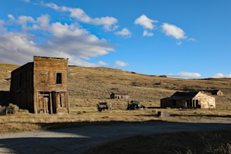 an old wooden building sitting in the middle of a field