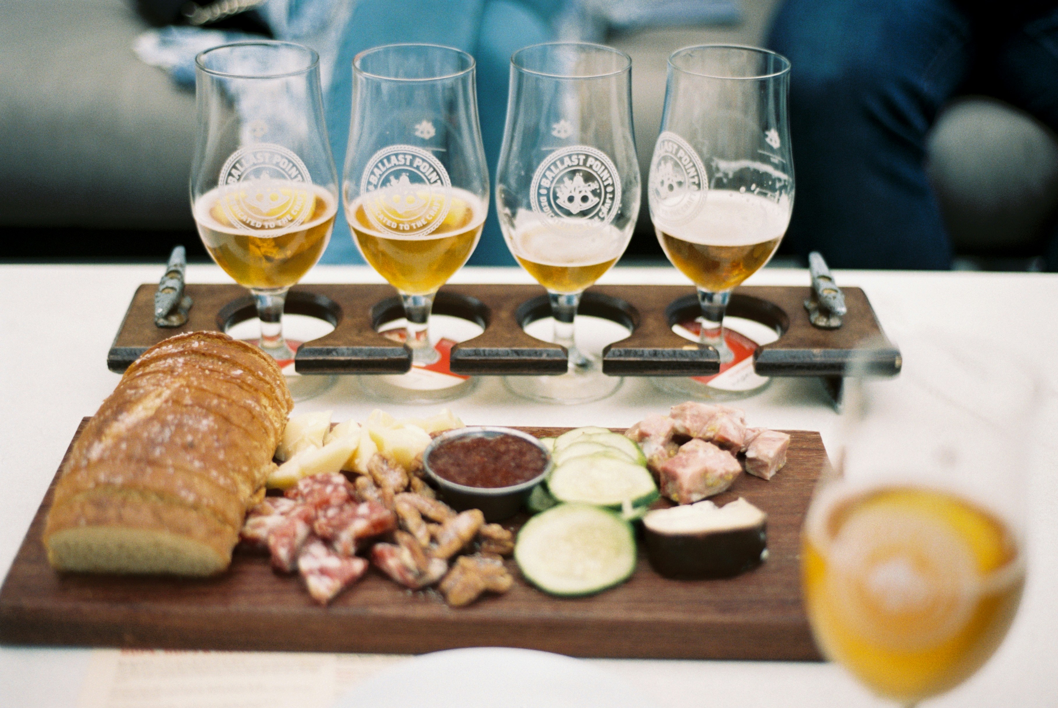 glass of white wine in glass near food and sliced bread on chopping board