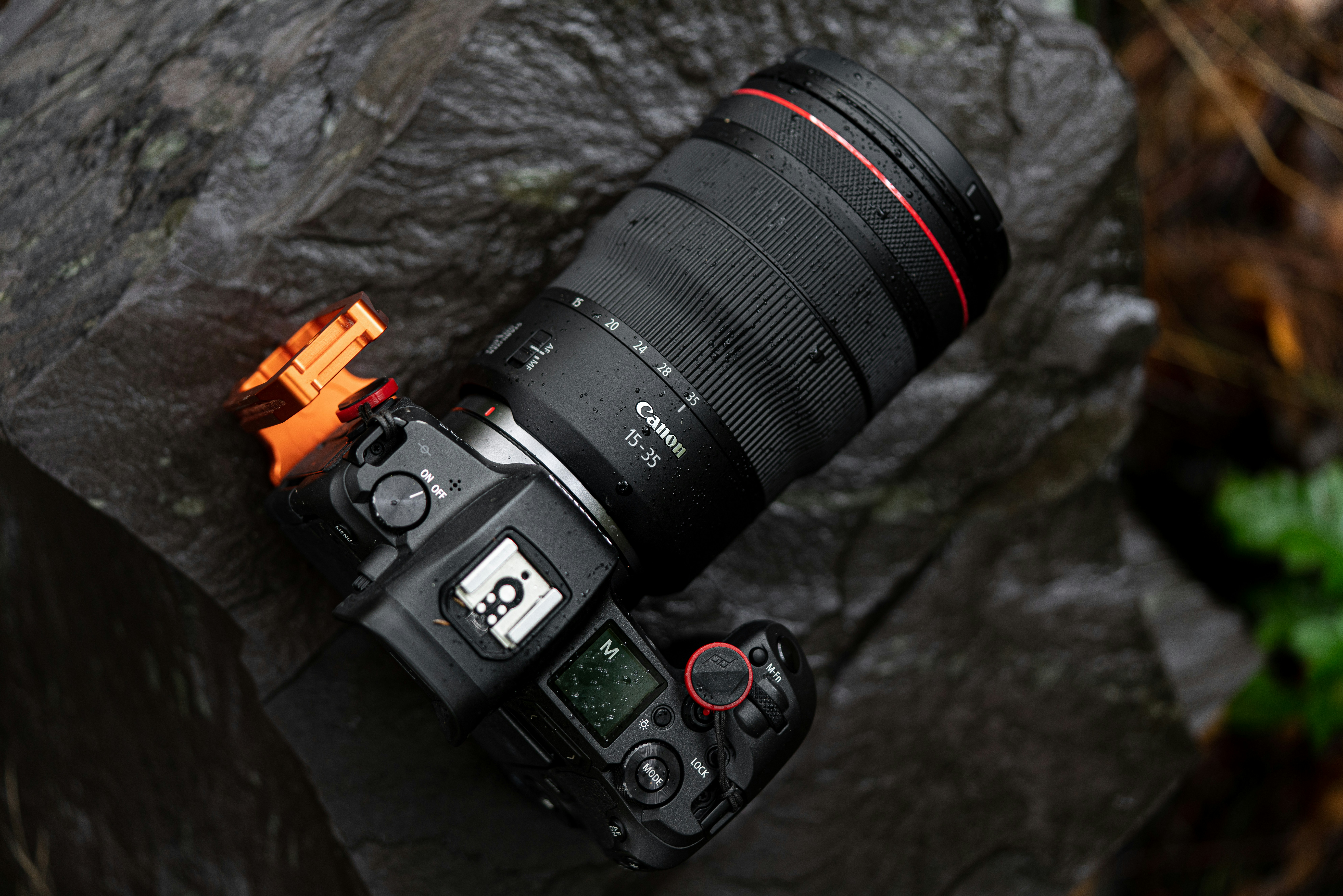 a camera sitting on top of a rock next to a fire