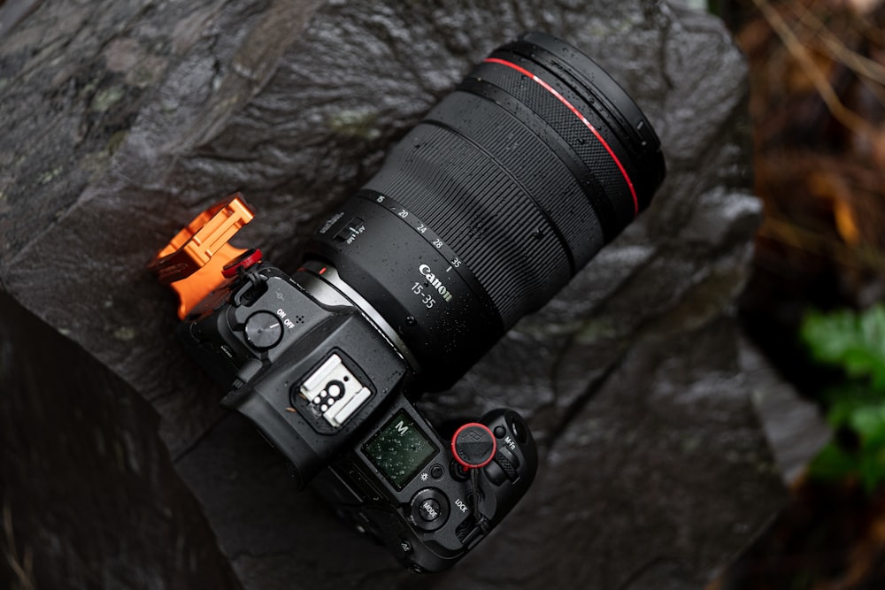 a camera sitting on top of a rock next to a fire