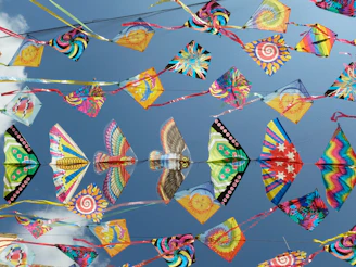 Colorful kites of various shapes and sizes displayed against a bright blue sky.