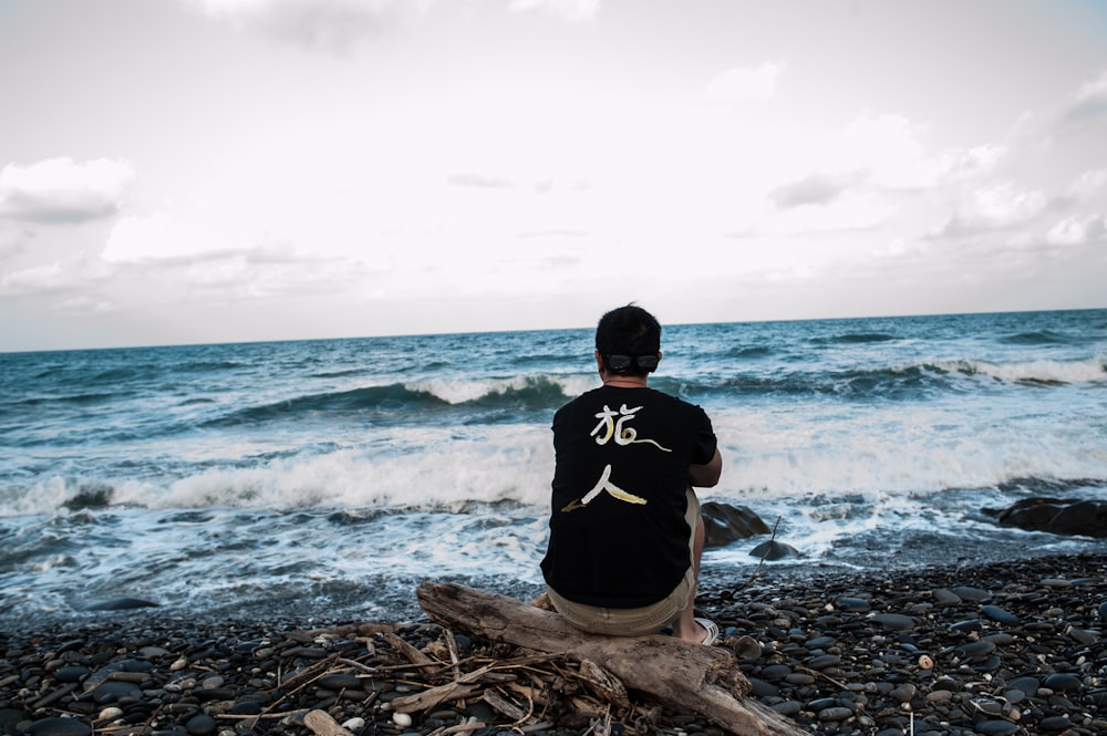 a man sitting on a log looking out at the ocean
