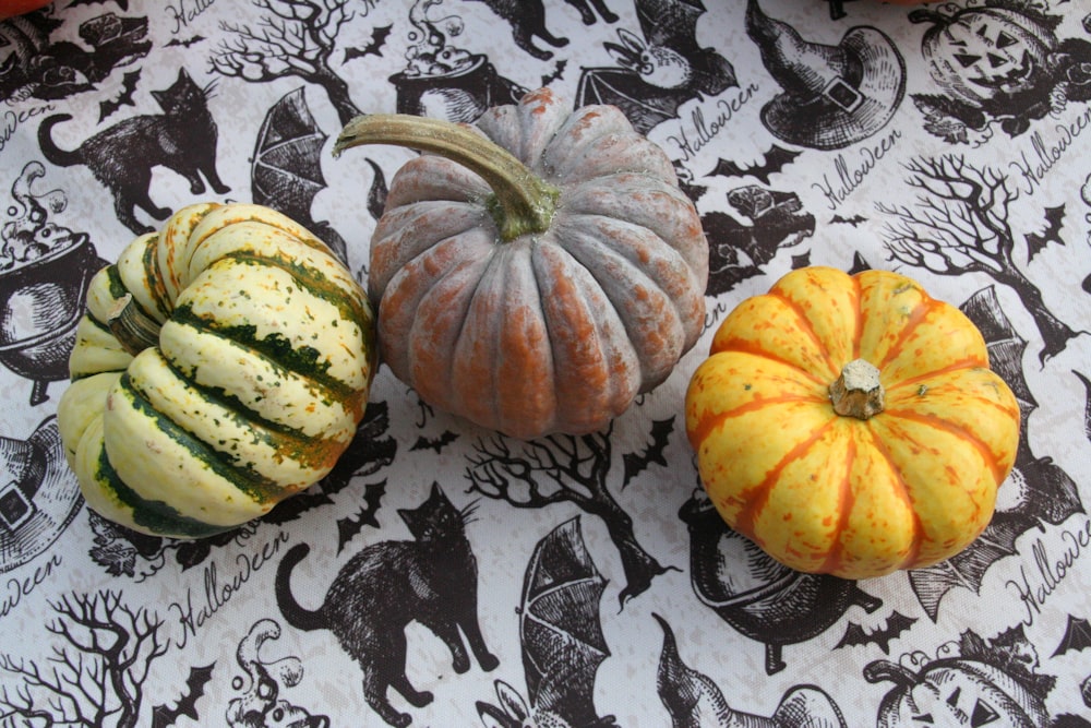 a group of three pumpkins sitting on top of a table