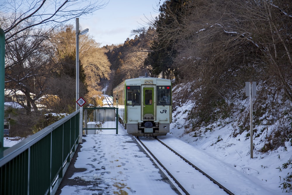 a green and white train traveling down train tracks