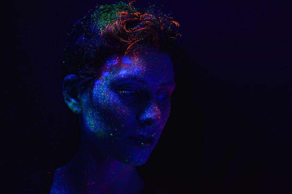Une femme dans une pièce sombre avec une lueur bleue et verte sur son visage