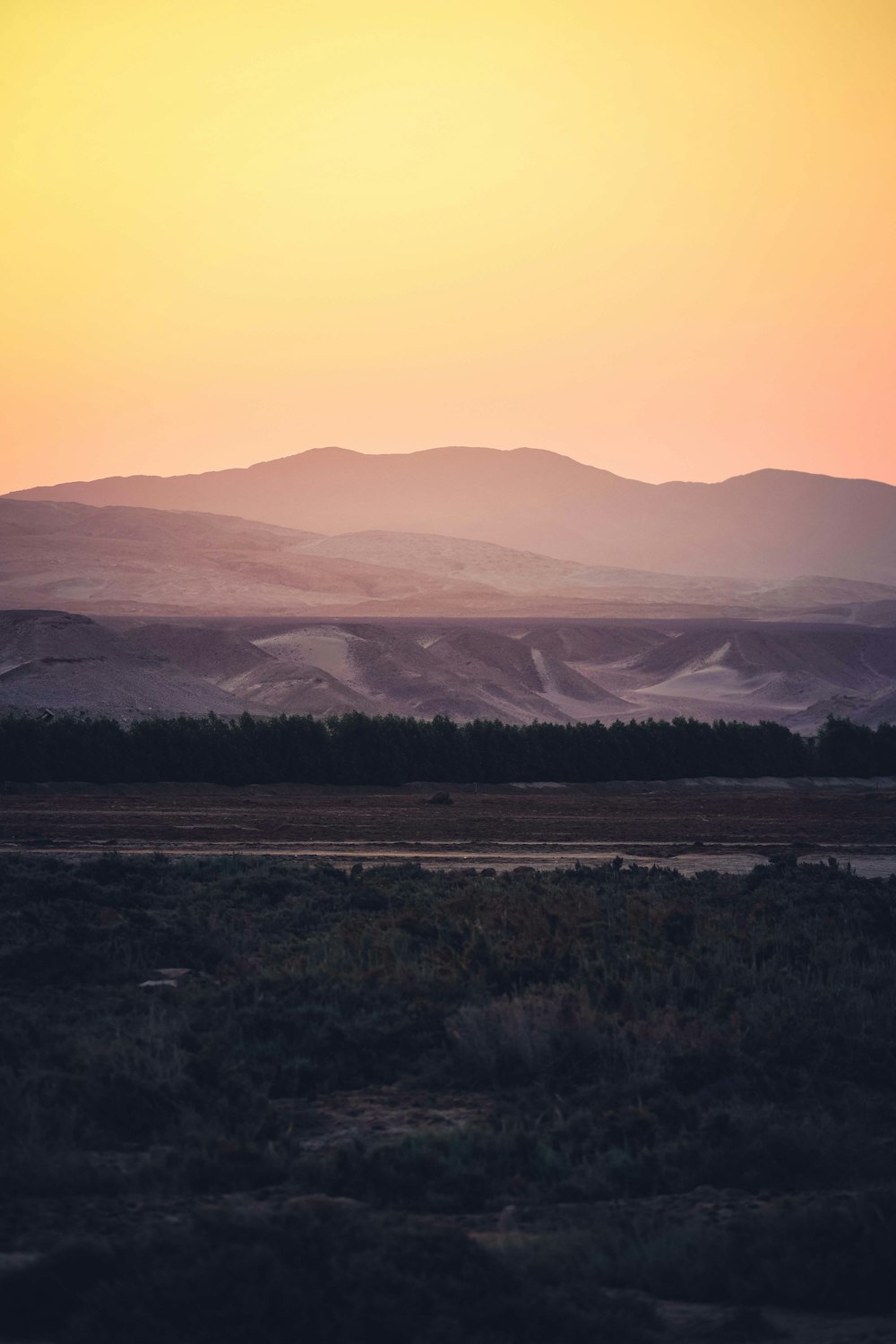 the sun is setting over the mountains in the distance