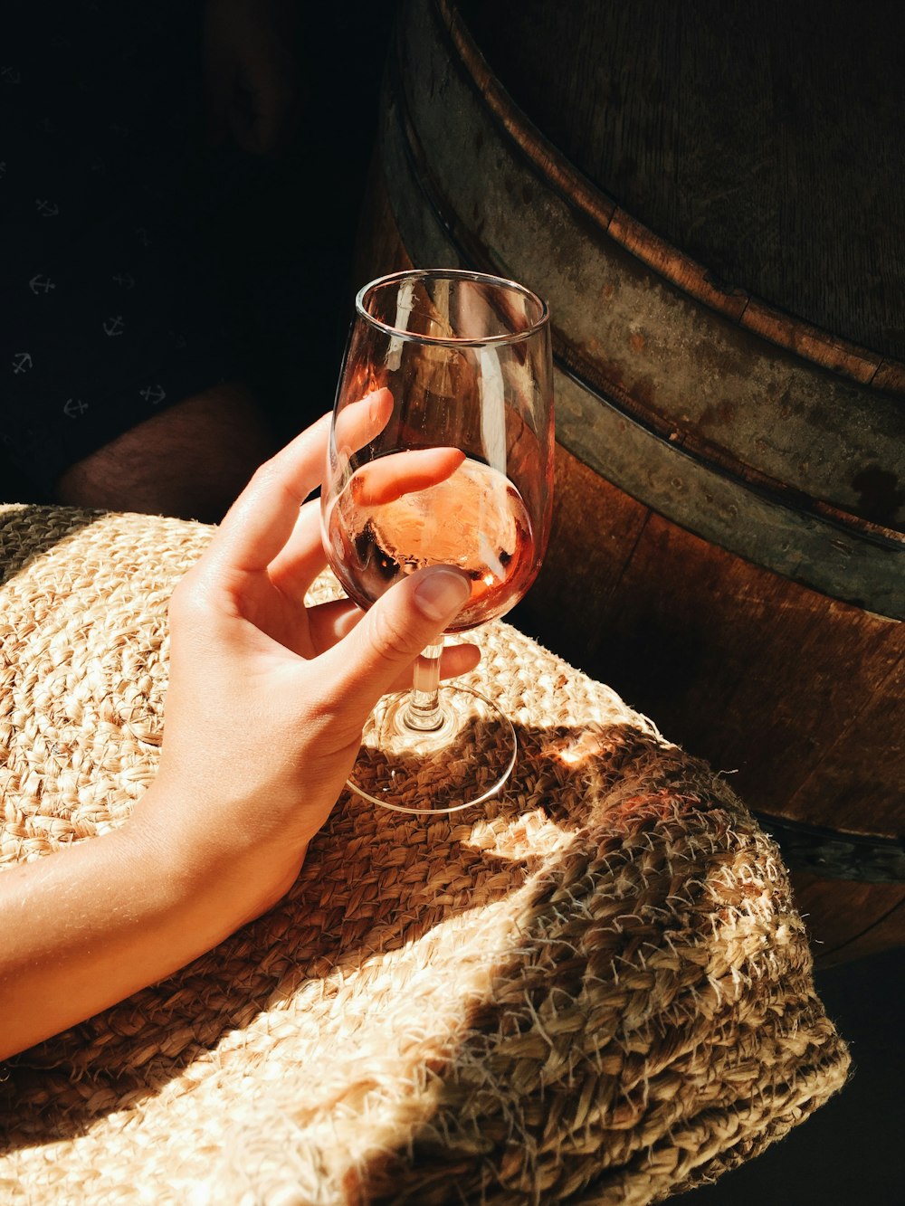 person holding glass of wine near barrel