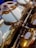 Close-up view of a brass instrument with detailed focus on the mechanism and keys, revealing polished, reflective surfaces with some signs of wear. The intricate parts are captured in warm lighting, highlighting the metallic texture.